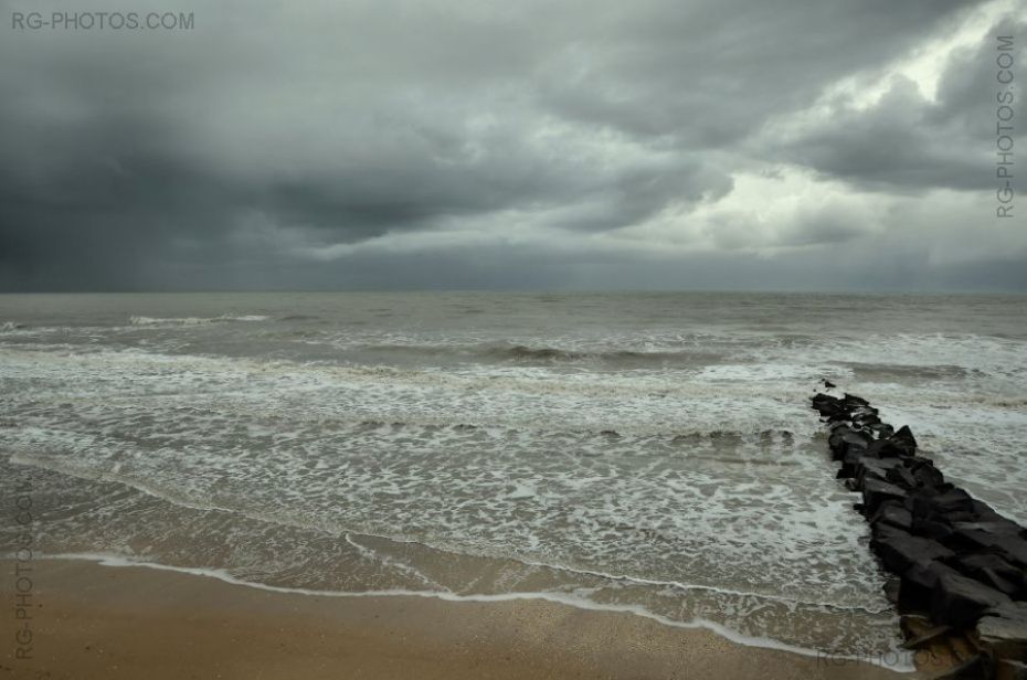 Epi noir s'enfonant dans la mer sous un ciel d'orage