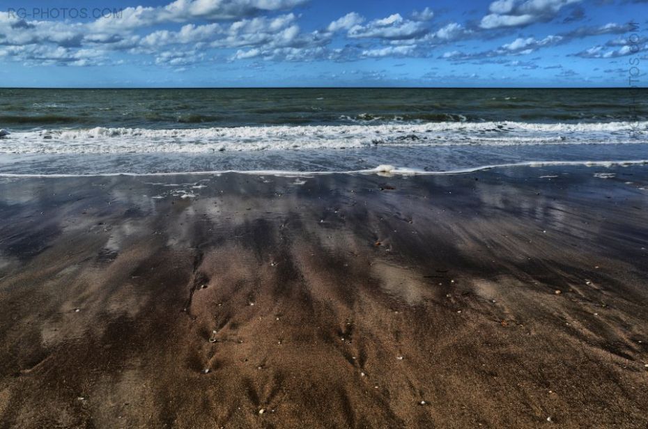 Reflet du ciel bleu sur sable mouill par les vagues